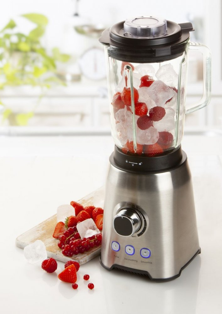 A stainless steel blender filled with ice and strawberries and red berries.