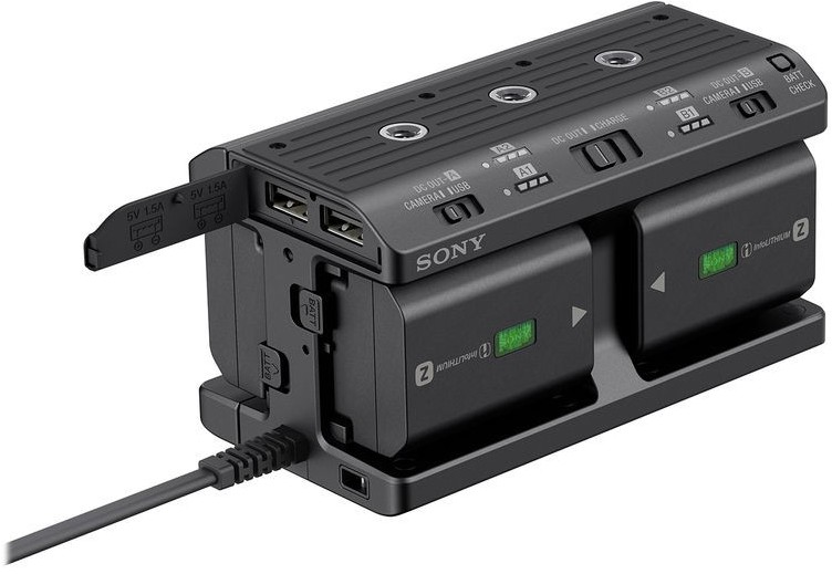 Chargeur de batterie Sony noir avec deux batteries et ports USB sur fond blanc.