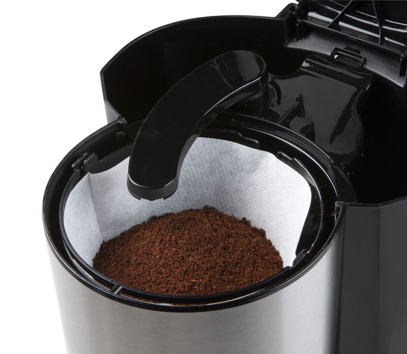 Close-up of a coffee maker filter with coffee grounds. Silver and black device.