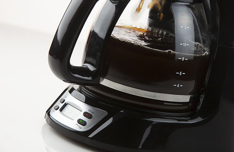A black coffee maker with a glass carafe filled with coffee, and a digital display.