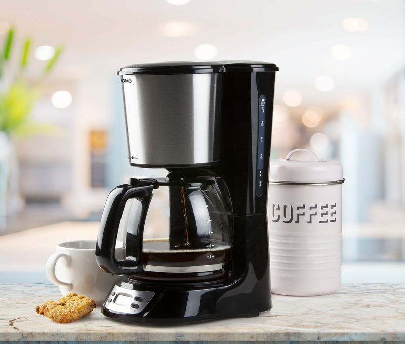 Coffee maker with a coffee pot and a cookie.