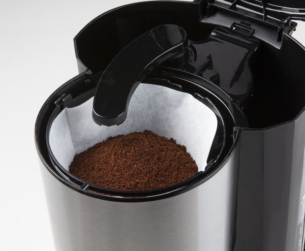 A black and silver coffee maker with ground coffee in a filter, close-up shot.
