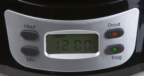 Close-up of a coffee maker display showing the time: 12:00.