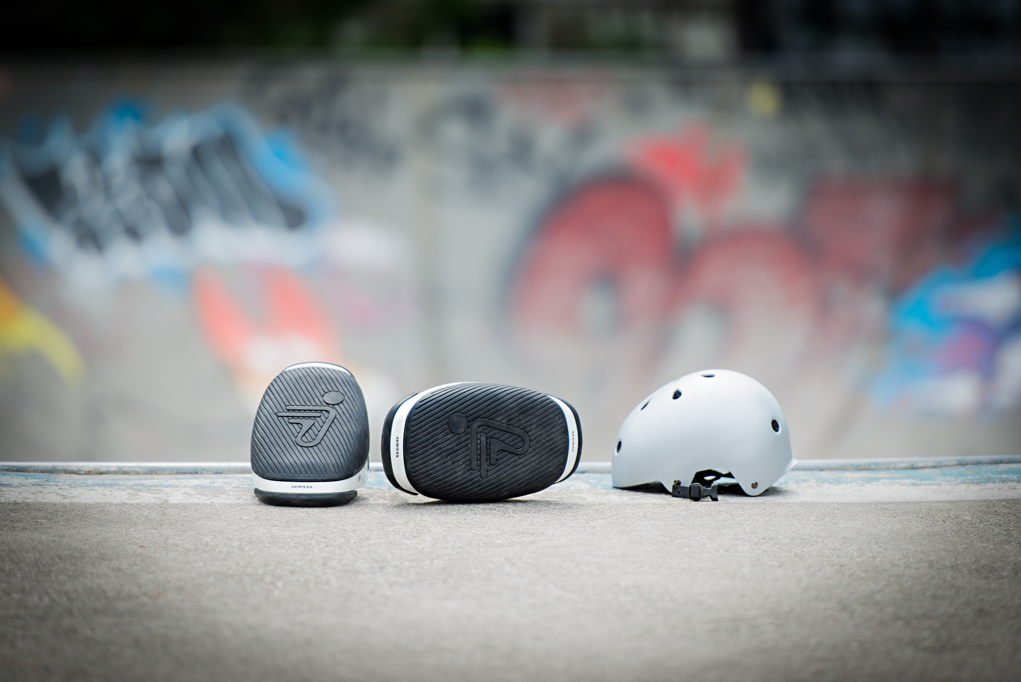 Eine Gruppe von drei schwarz-weißen Kopfhörern und einem weißen Helm auf Beton.