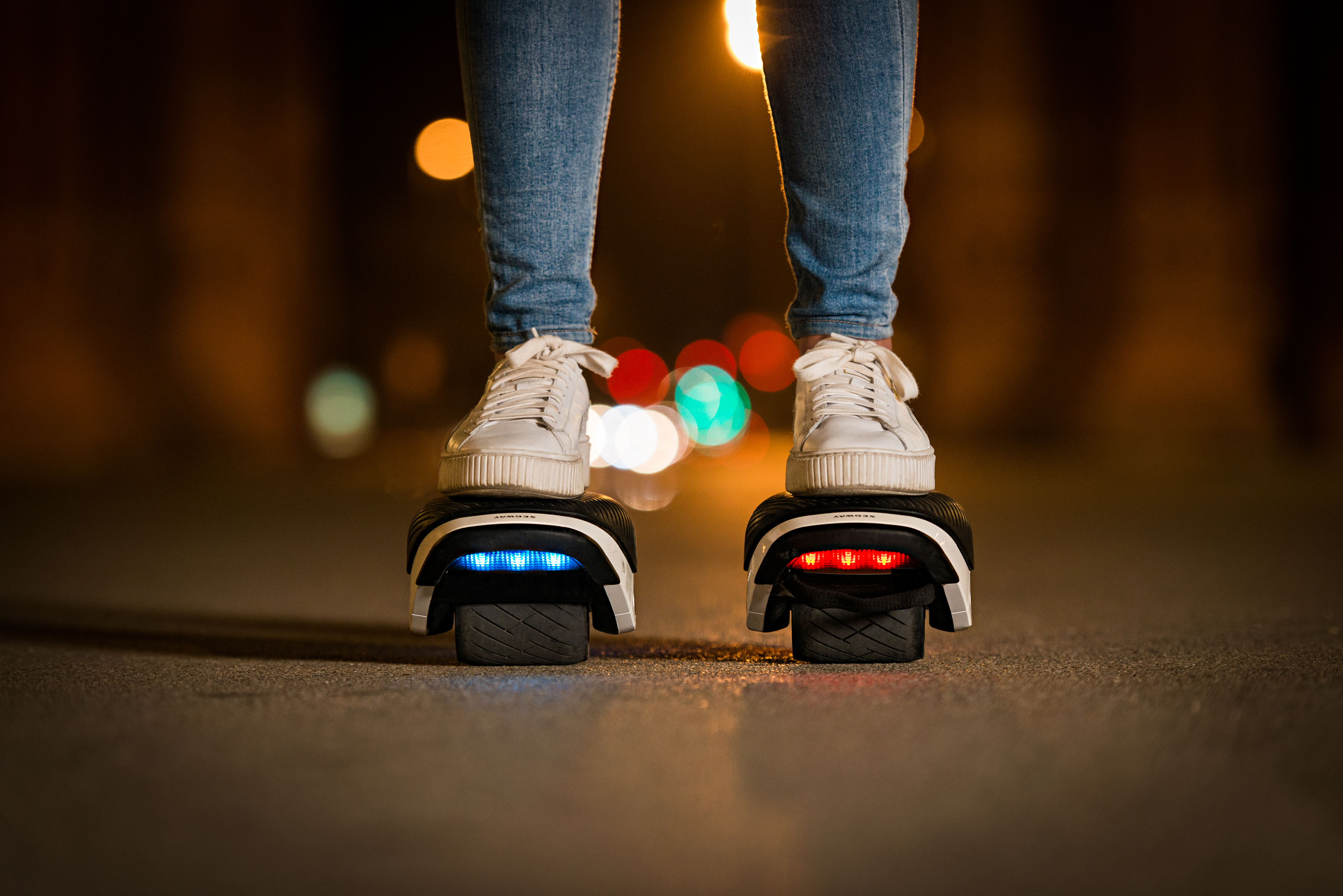 Eine Person steht nachts auf zwei selbstausgleichenden Elektrorollern.