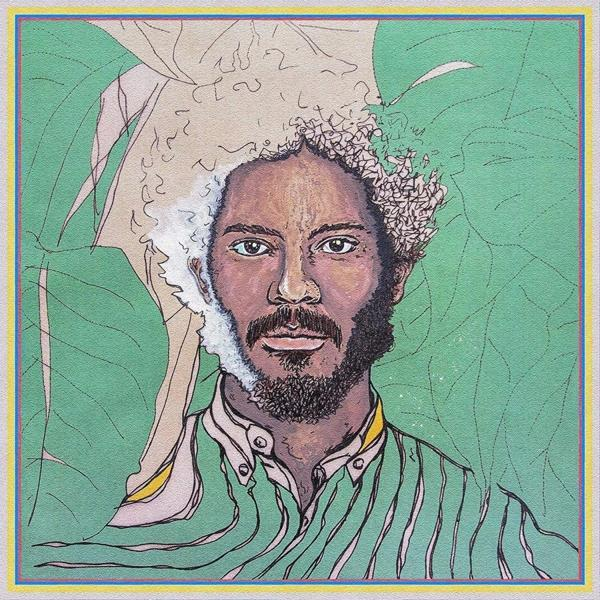 Portrait d'un homme avec la moitié de ses cheveux et de sa barbe blancs, entouré de feuilles vertes.