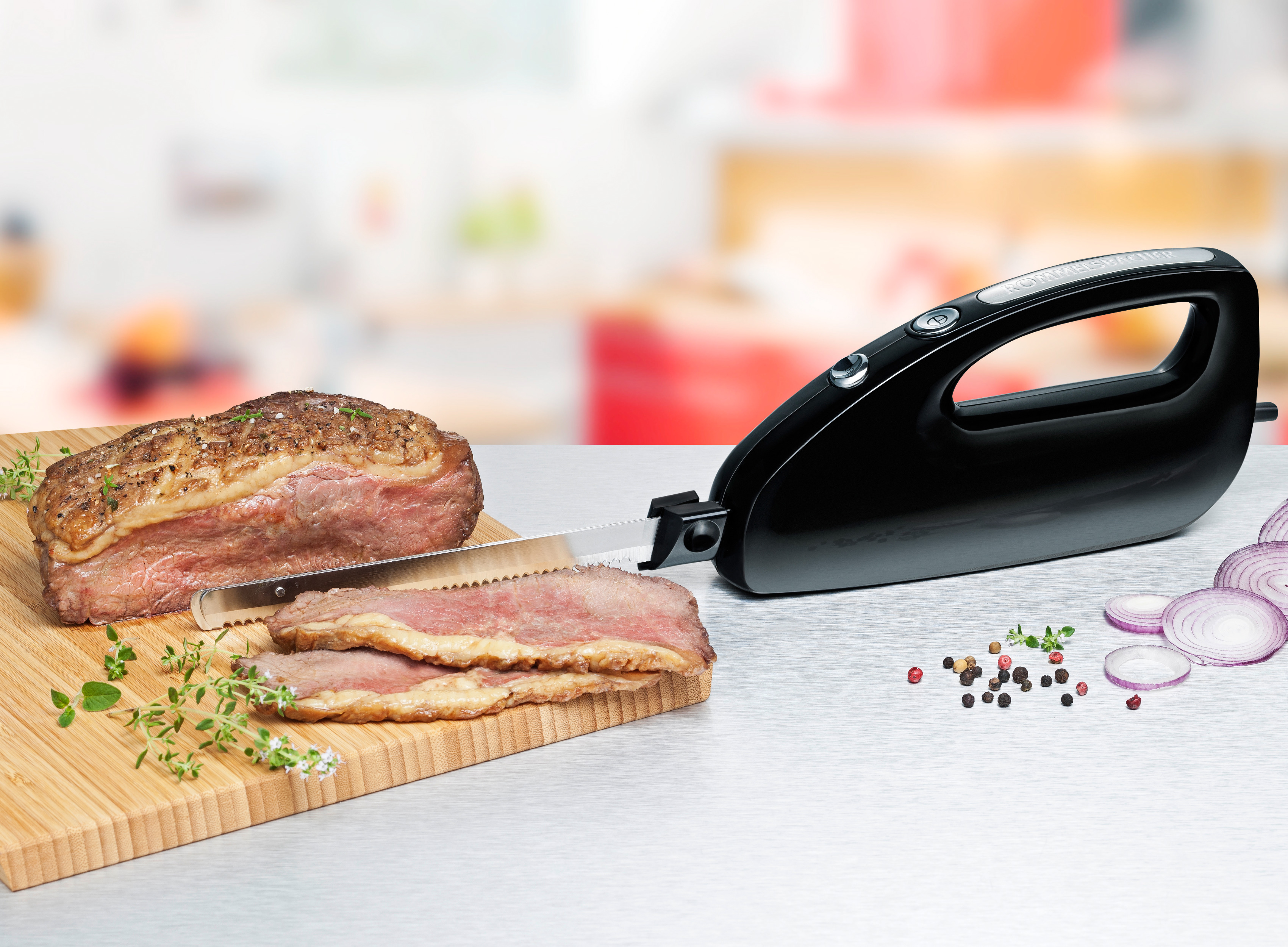 Elektrisches Messer schneidet Braten. Geschnittenes Fleisch auf Holzbrett, Gemüse daneben.
