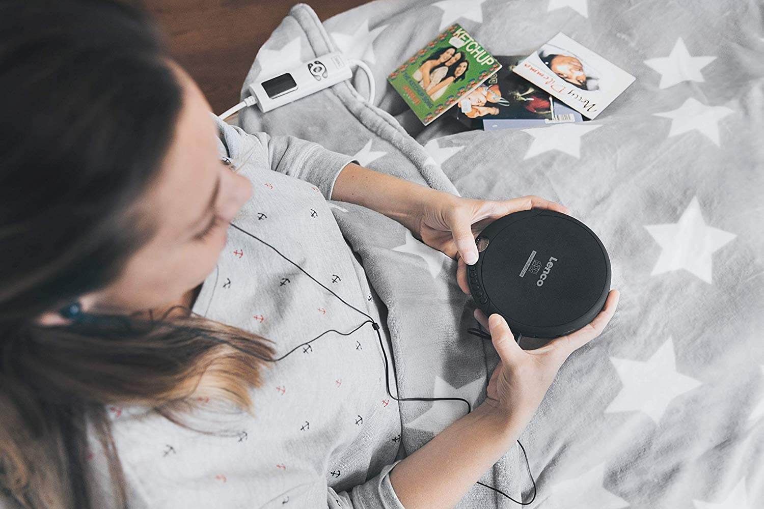 Woman listening to music with a black Lenco CD player on a star blanket.