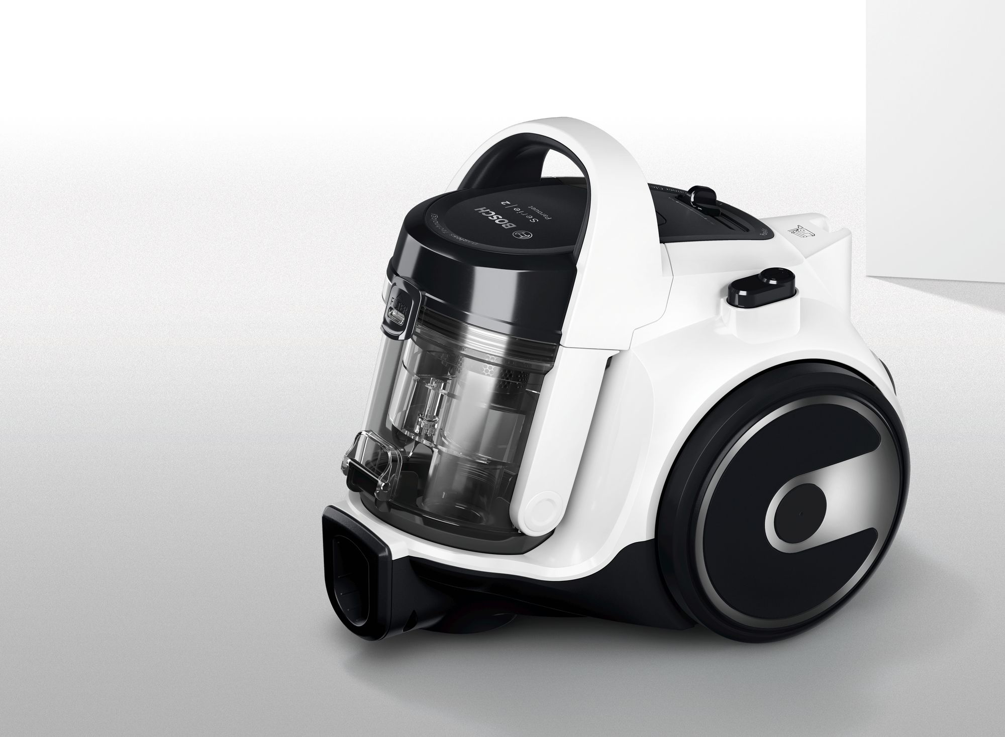 A white and black vacuum cleaner, with a transparent dust container, on a white surface.