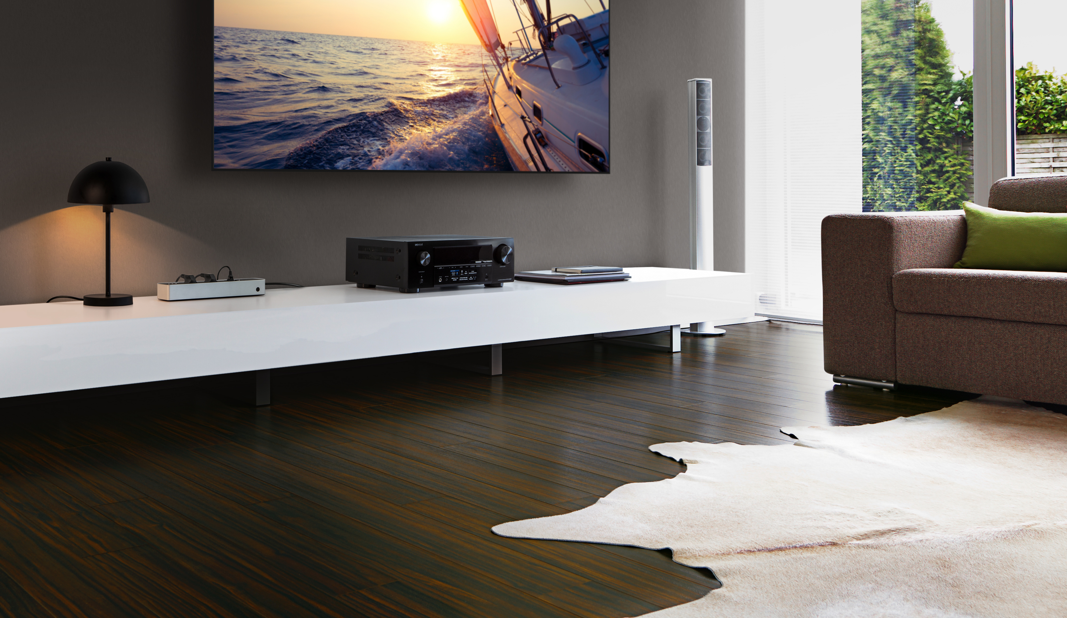 Wohnzimmer mit Fernseher, Soundsystem und Sofa. Ein Boot ist auf dem Bildschirm. Holzboden mit Kuhfellteppich.