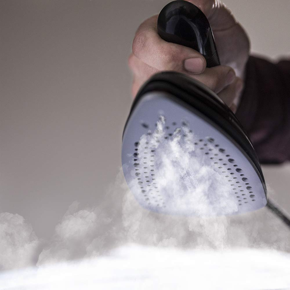 Plancha emitiendo vapor, sostenida por una mano. El vapor sube.