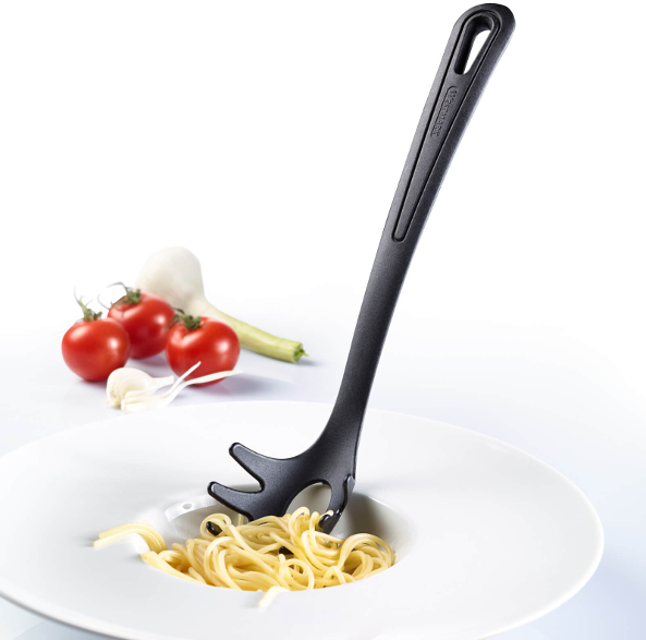 Egy fekete spagetti kanál tésztával egy fehér tálban, paradicsommal, fokhagymával és zöldhagymával.