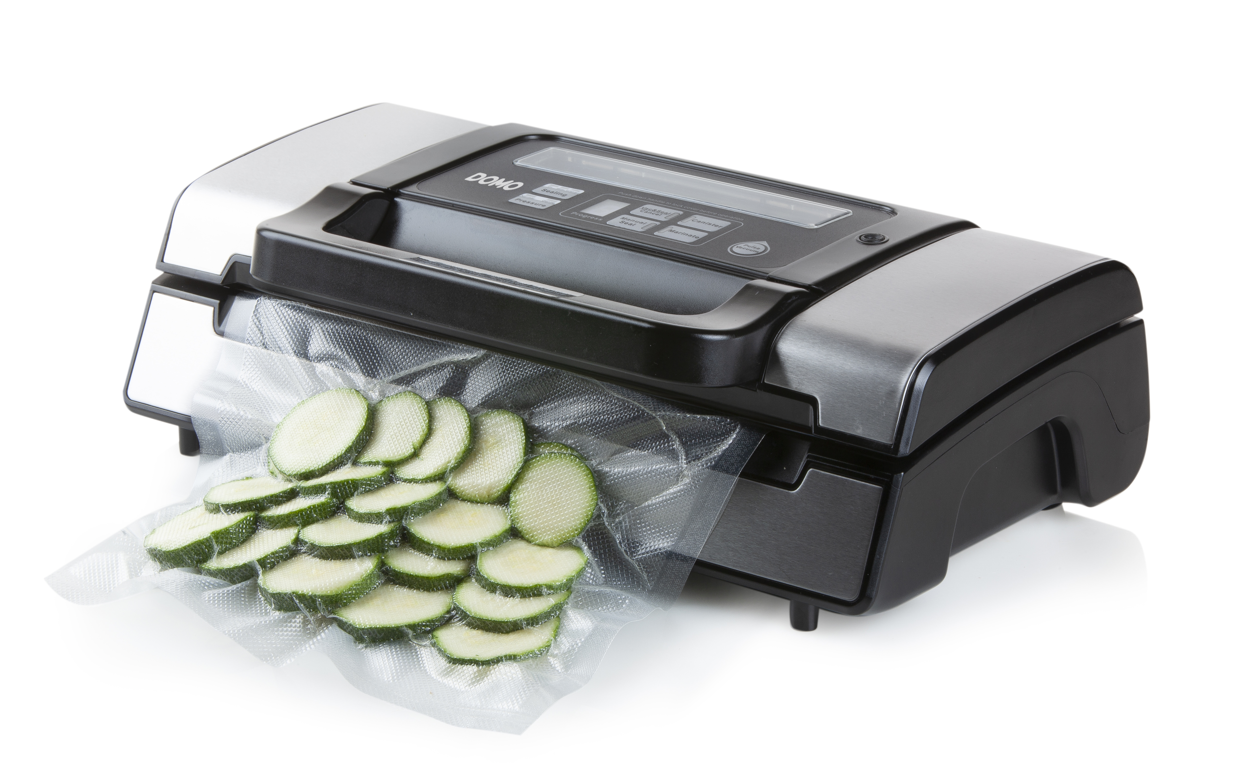 Une scelleuse sous vide avec des courgettes tranchées dans un sac. L'appareil est argenté et noir.