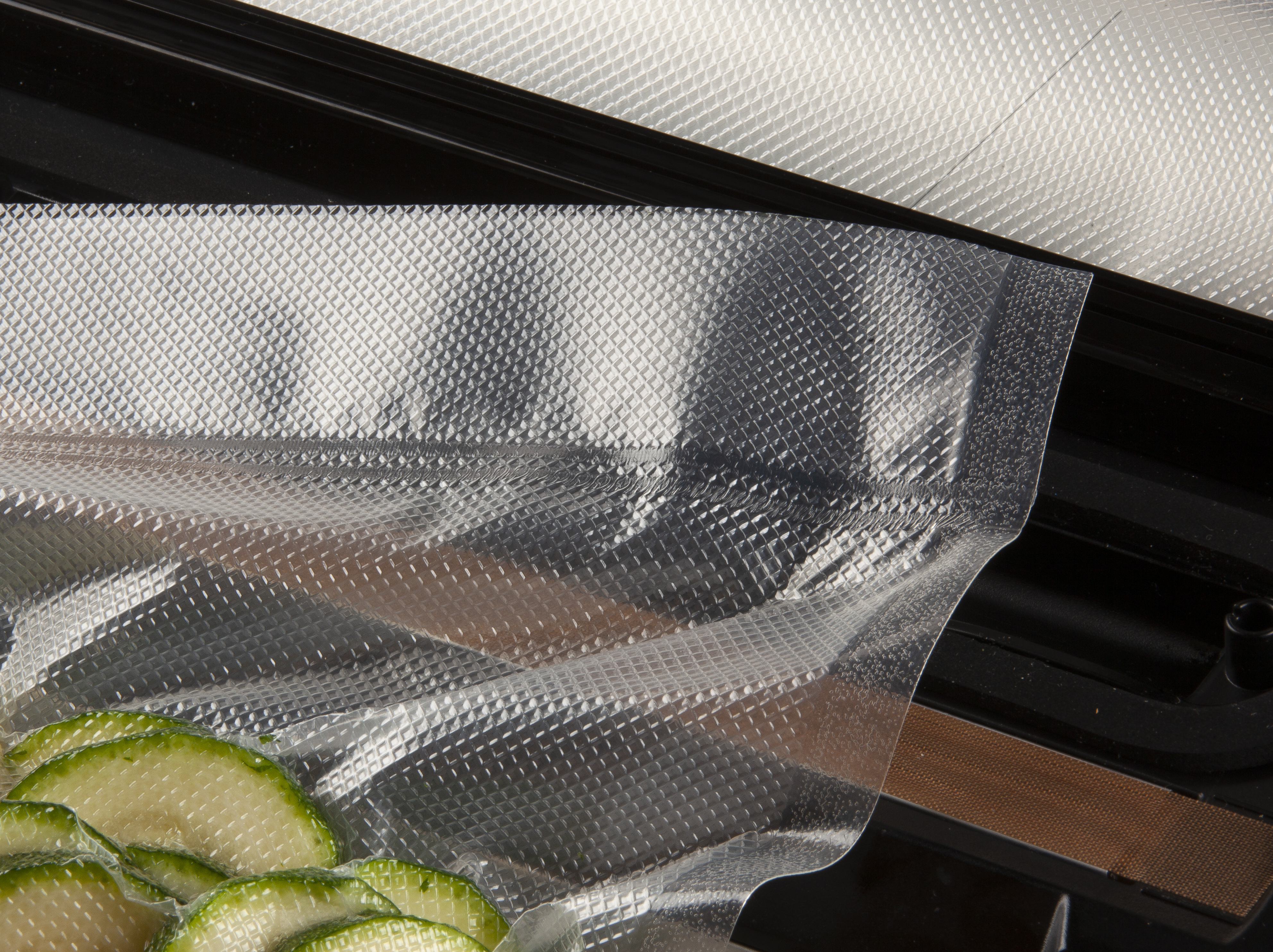Tranches de courgettes dans un sac sous vide sur une machine sous vide noire.