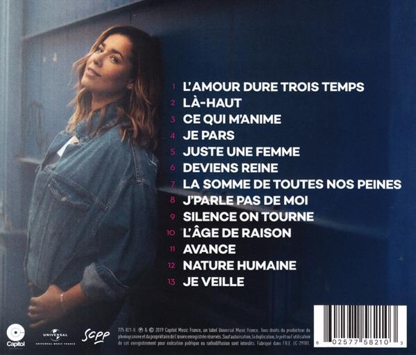 Femme appuyée contre un mur bleu. Pochette d'album avec titres de chansons en blanc.