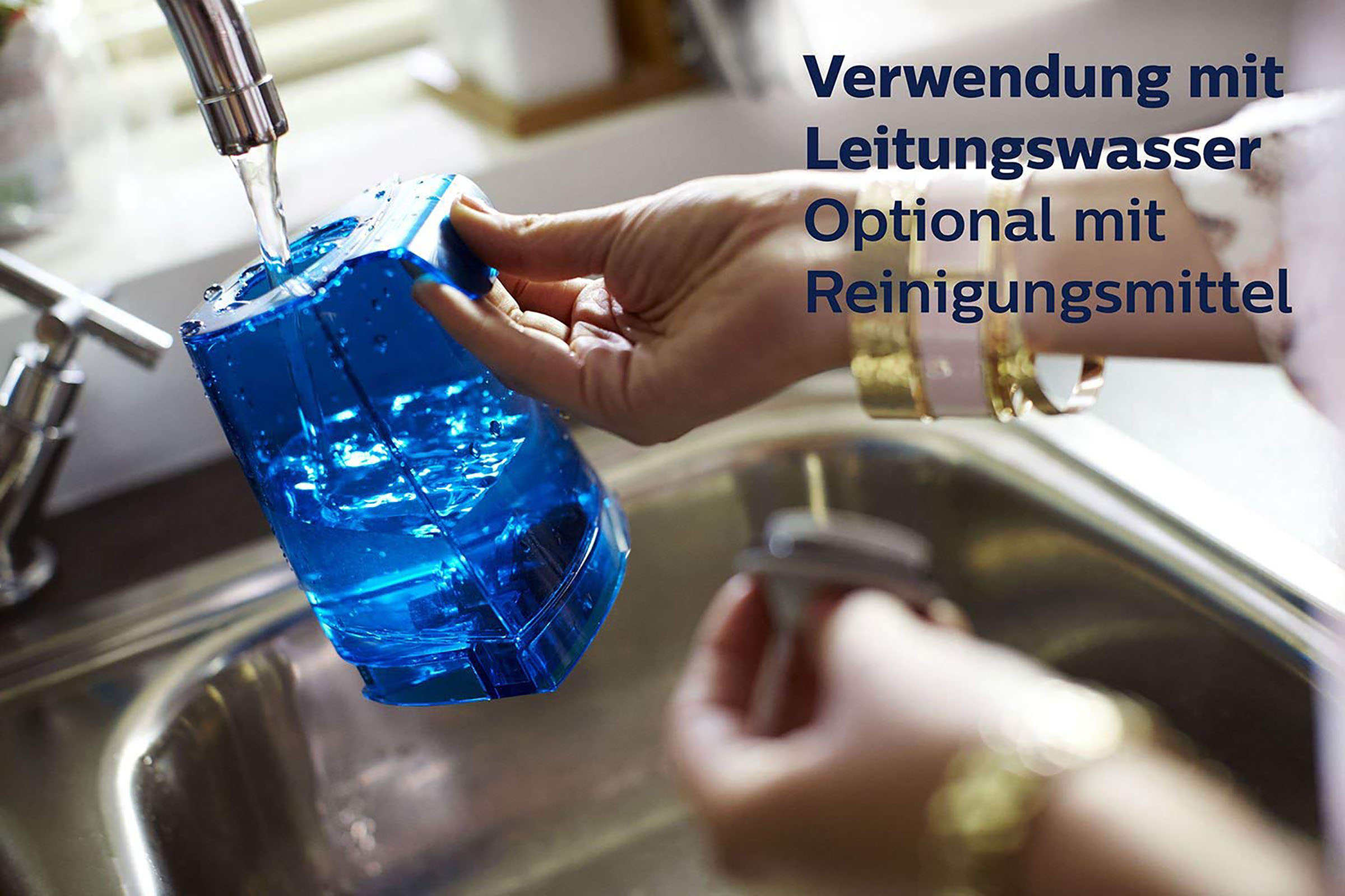 Eine Person füllt einen blauen Behälter mit Wasser aus einem Wasserhahn über einem Waschbecken. Text auf Deutsch ist sichtbar.