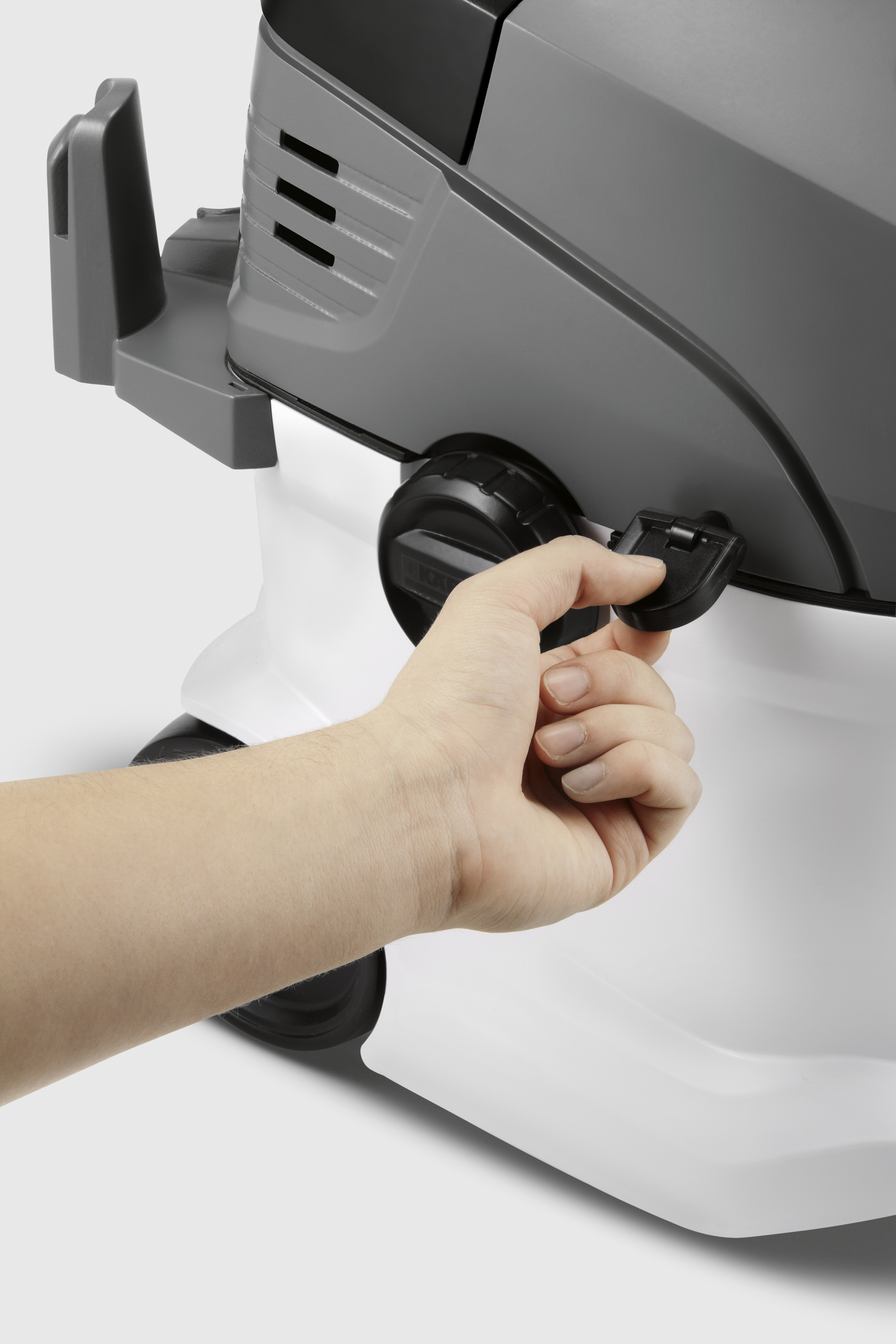 Die Hand einer Person bedient einen Riegel an einem weiß-grauen Staubsauger.