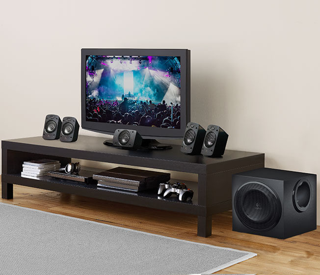 Sehpada TV, hoparlörler ve subwoofer bulunan oturma odası. TV açık ve konser gösteriyor.