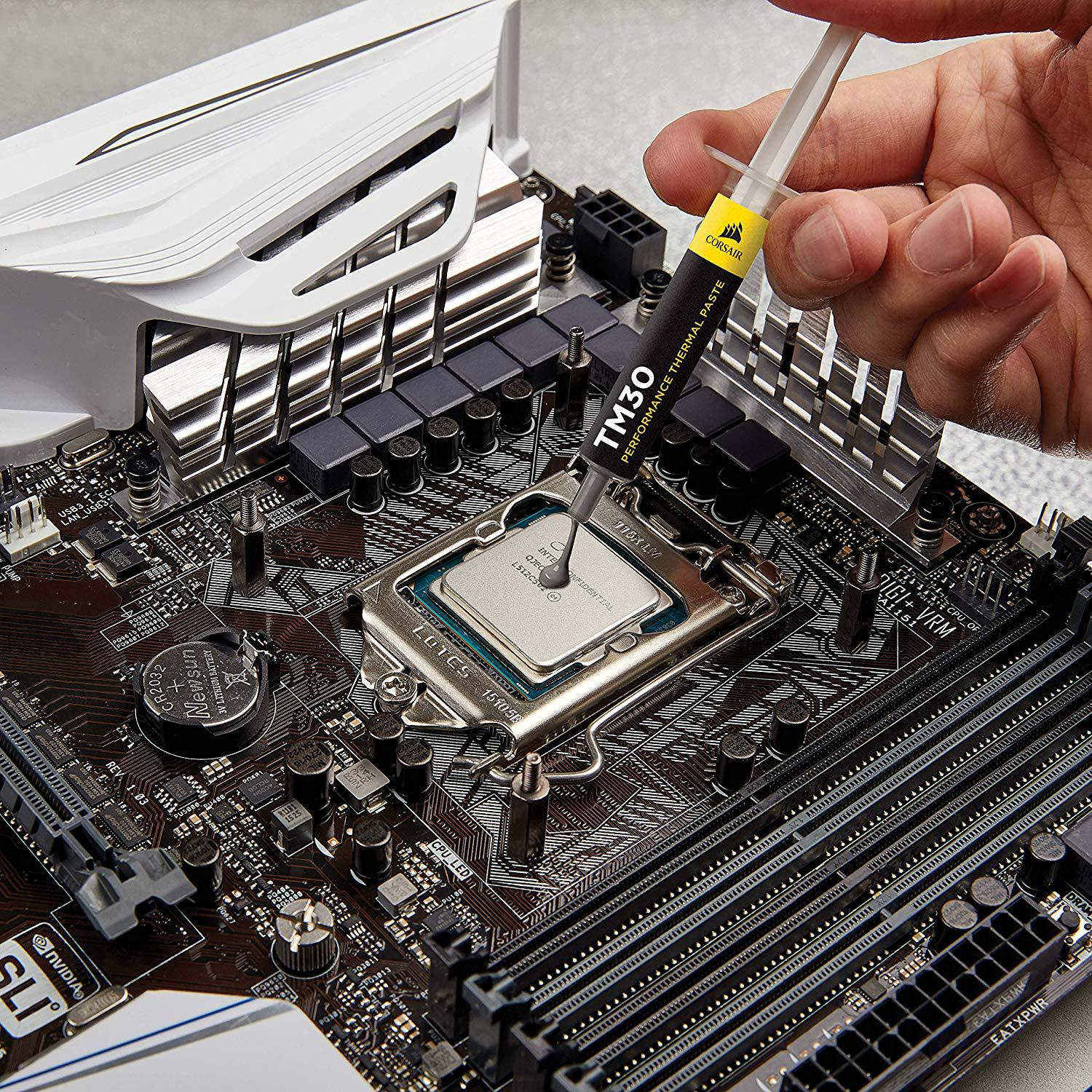 Hand trägt Wärmeleitpaste auf CPU auf Motherboard auf.