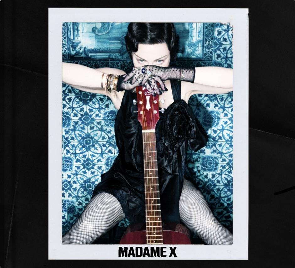 Madonna mit Gitarre, Foto in einem Polaroid-Rahmen. Über einer gemusterten Wand.