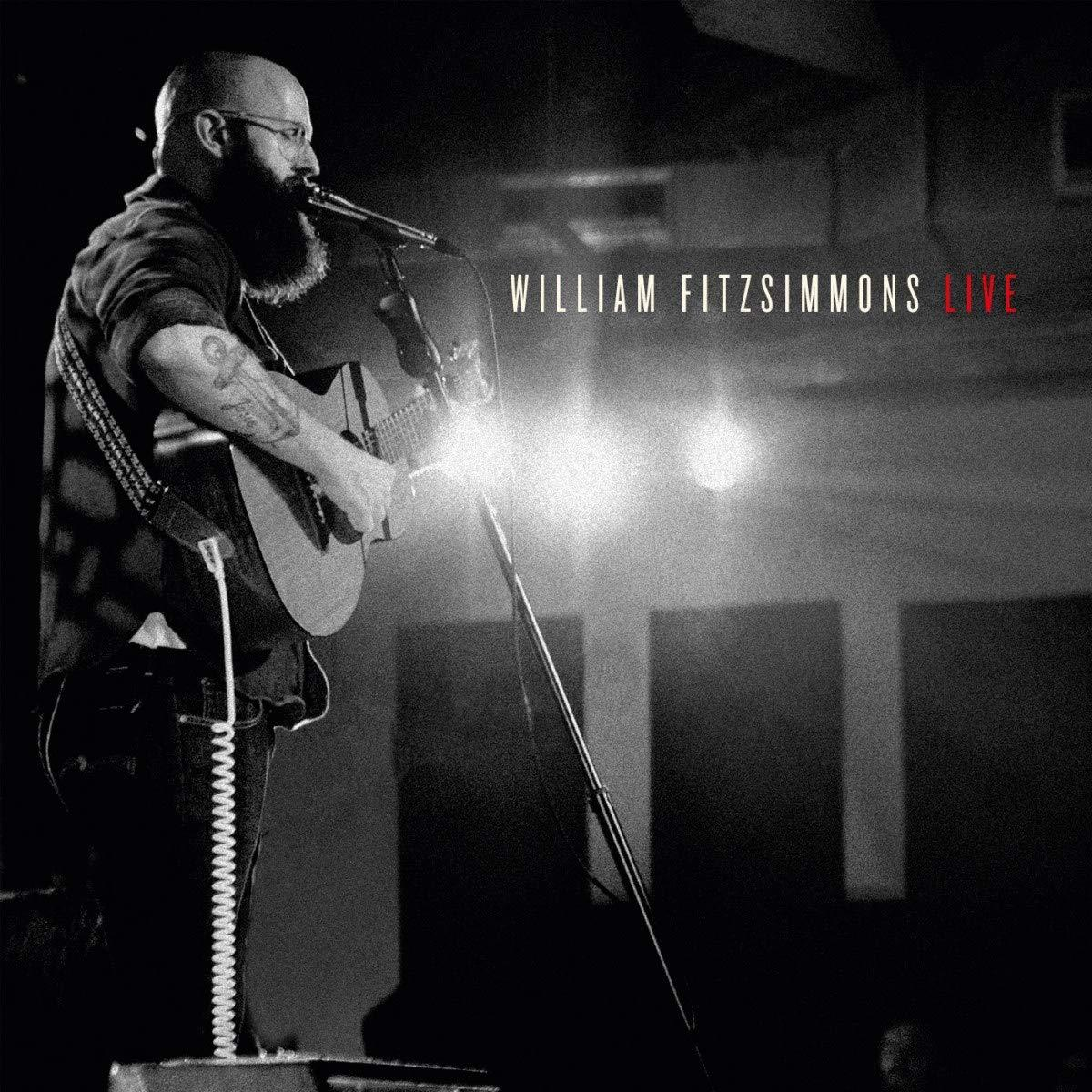 Eine Live-Performance mit einem glatzköpfigen Mann, der Gitarre spielt und in ein Mikrofon singt, mit dem Text 'WILLIAM FITZSIMMONS LIVE'.