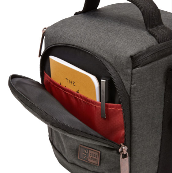 Gray camera bag with open pocket, notebook, and pen. Case Logic logo visible.