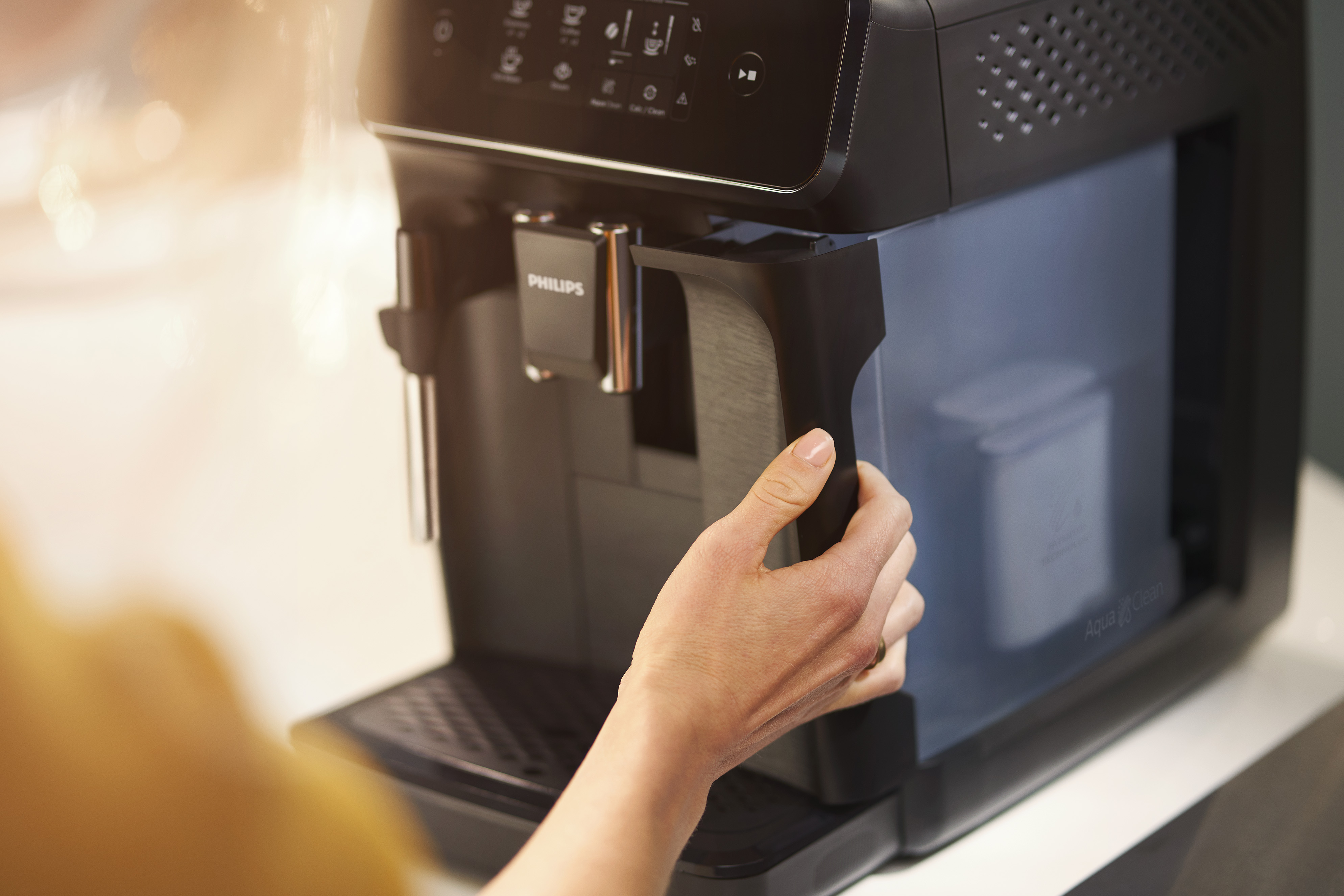 Die Hand einer Person, die den Wassertank aus einer schwarzen Kaffeemaschine nimmt.