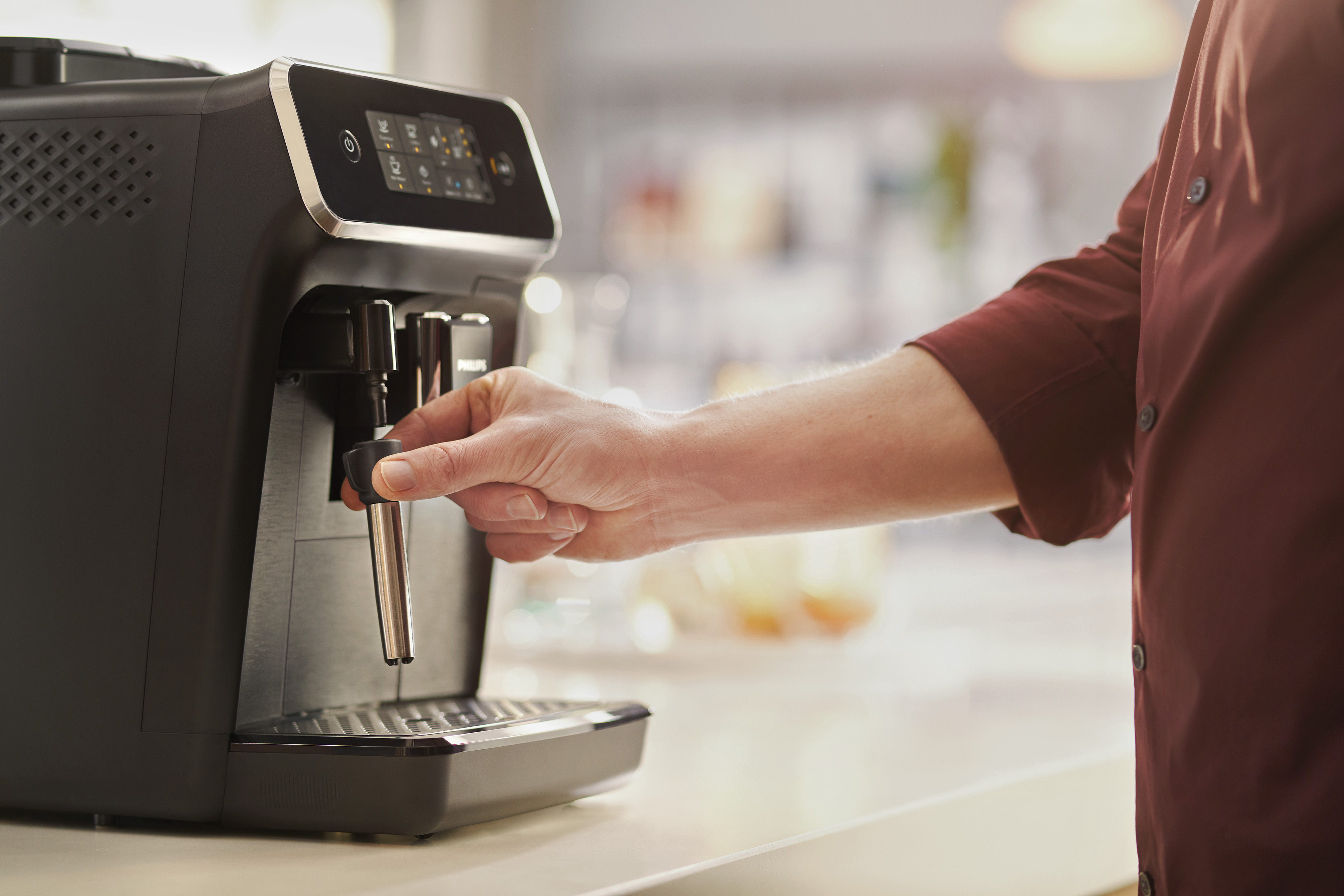 Eine Person, die eine schwarze Philips-Kaffeemaschine benutzt und eine Taste drückt.