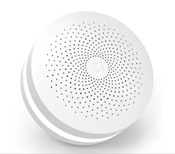 Dispositivo doméstico inteligente blanco y redondo con muchos agujeros y un logotipo.