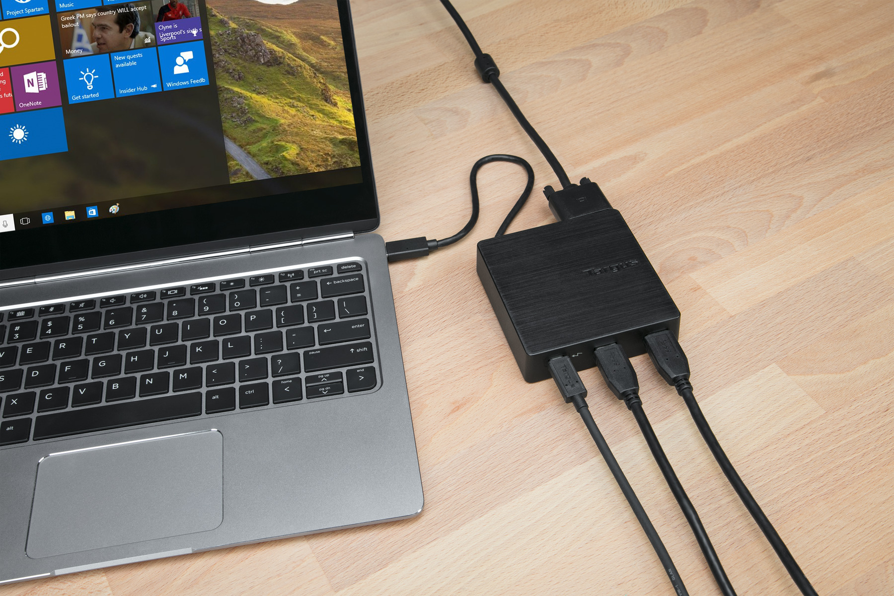 Laptop mit einem schwarzen USB-Hub mit drei angeschlossenen USB-Kabeln.