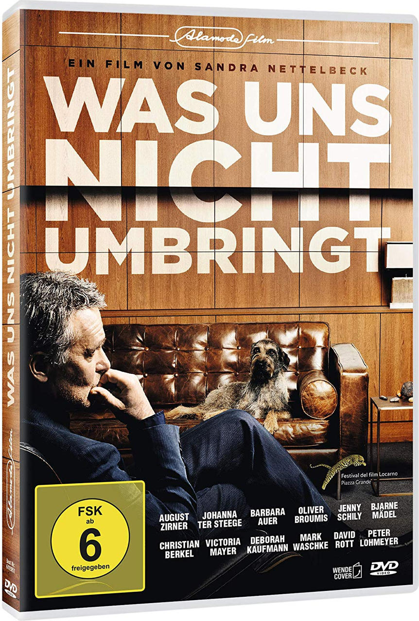 Film-DVD-Cover. Mann auf Couch, Hund, Titel: Was Uns Nicht Umbringt. Braune Töne, Holz Hintergrund.