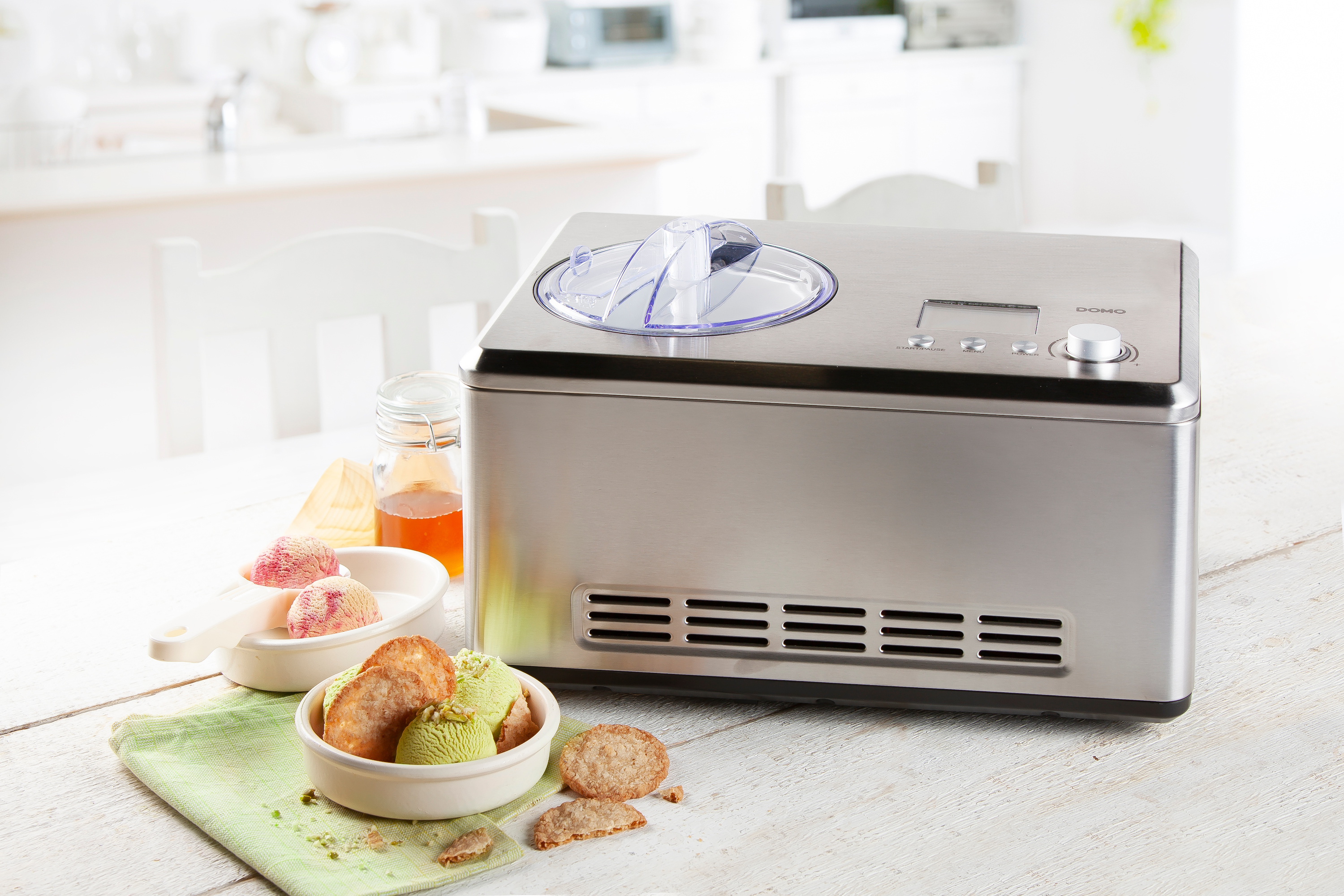 Machine à crème glacée avec crème glacée et biscuits sur table bois.
