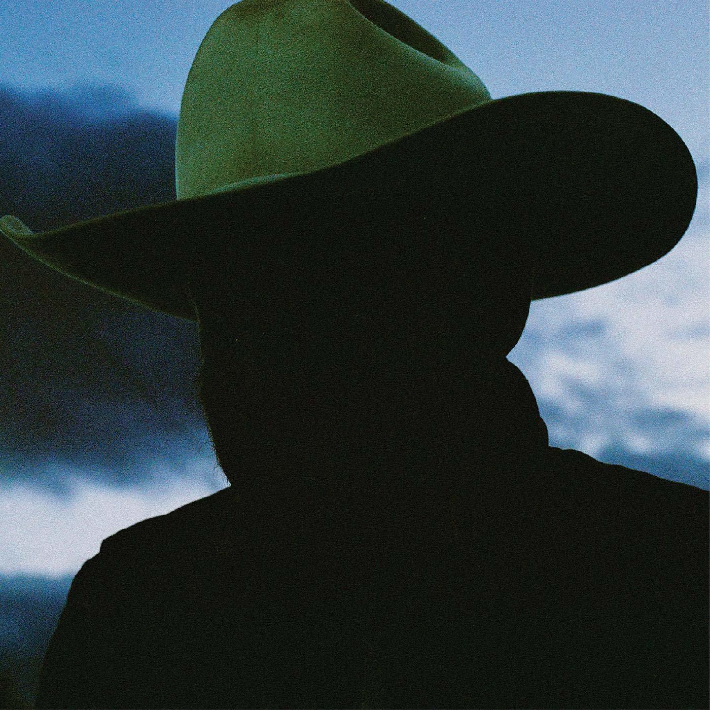 Silhouette eines Mannes mit Cowboyhut vor einem bewölkten blauen Himmel. Dunkles, mysteriöses Bild.