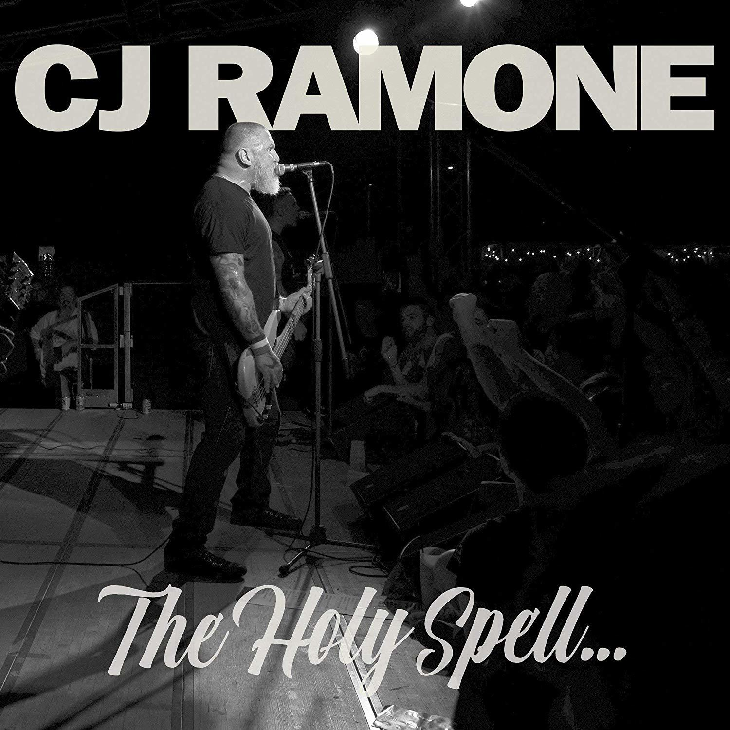 Schwarz-Weiß-Foto von CJ Ramone auf der Bühne, der Gitarre spielt, vor Publikum. Text: The Holy Spell.