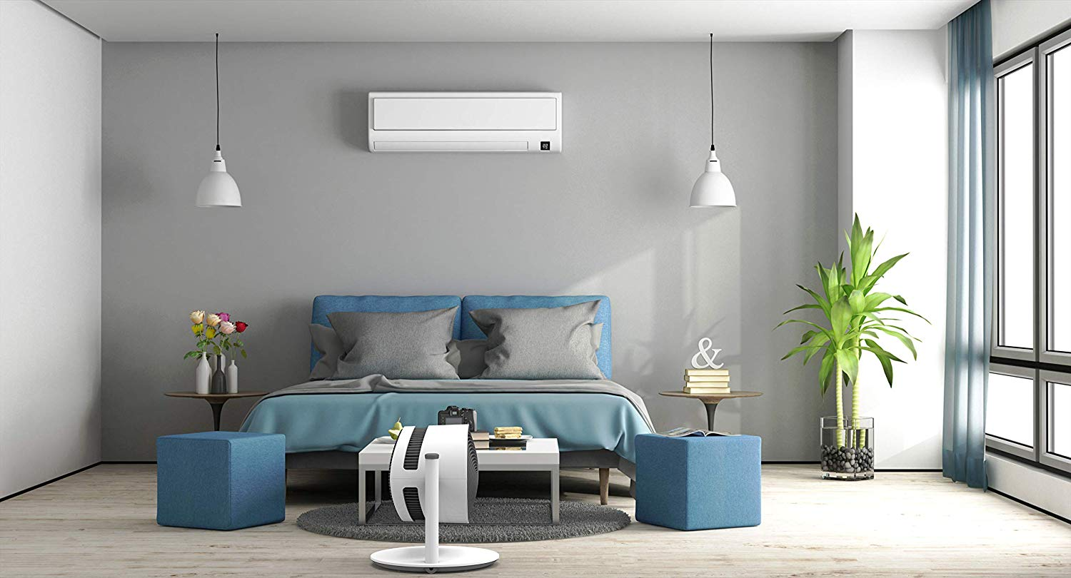 Chambre moderne avec murs gris, lit bleu et ventilateur sur table blanche. Deux lampes suspendues.