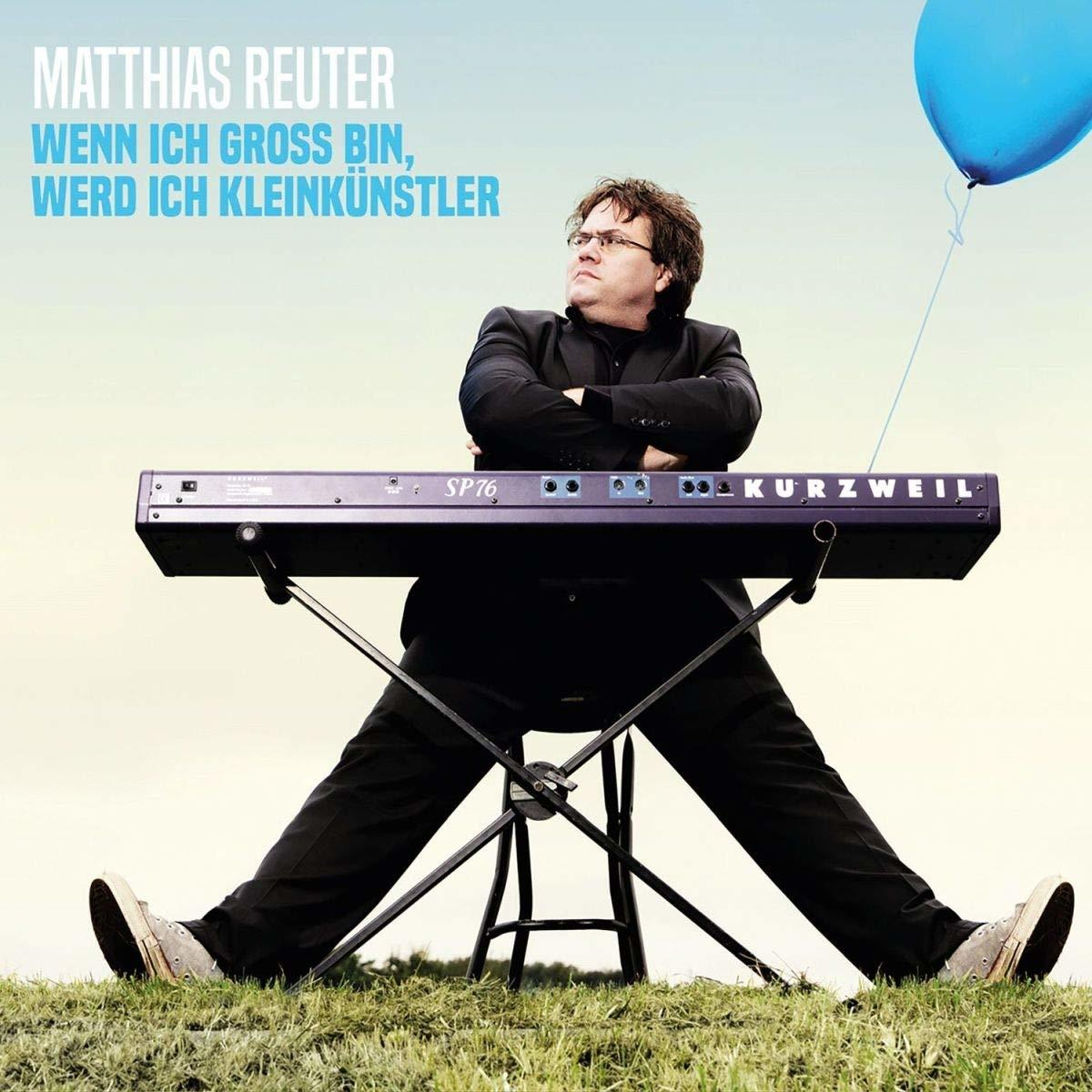 Mann sitzt auf einer Tastatur, mit einem blauen Ballon.