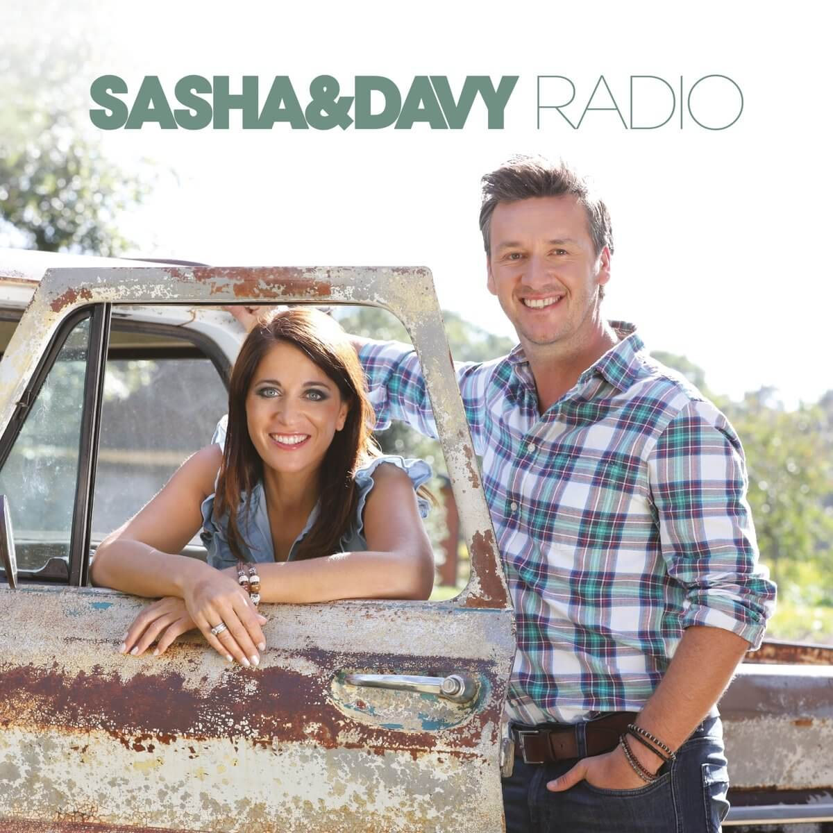 Twee mensen die glimlachen in een oldtimer, de tekst 'Sasha & Davy Radio'.