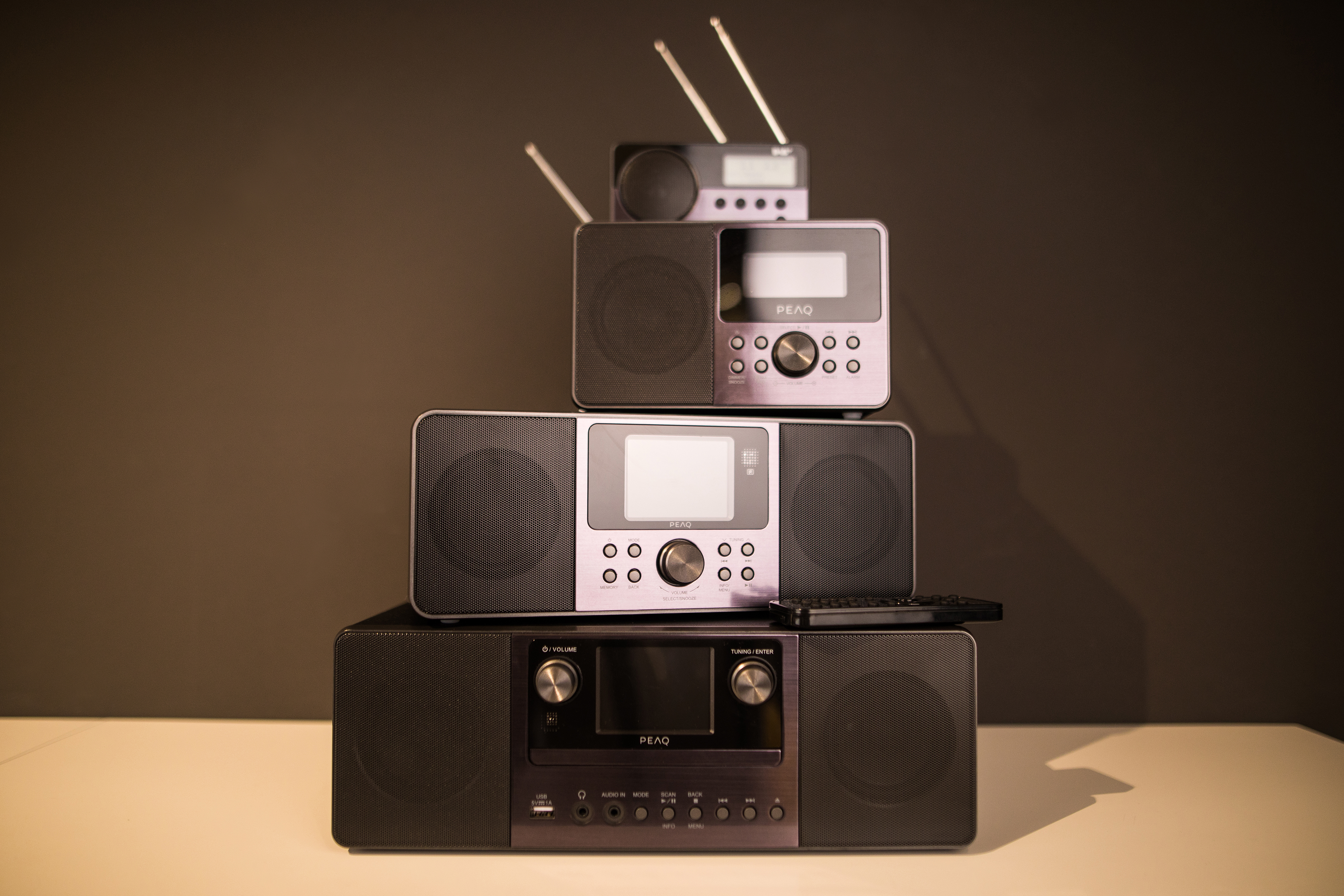 Vier Radios auf einer weißen Oberfläche vor dunklem Hintergrund gestapelt, jedes mit unterschiedlichem Design.