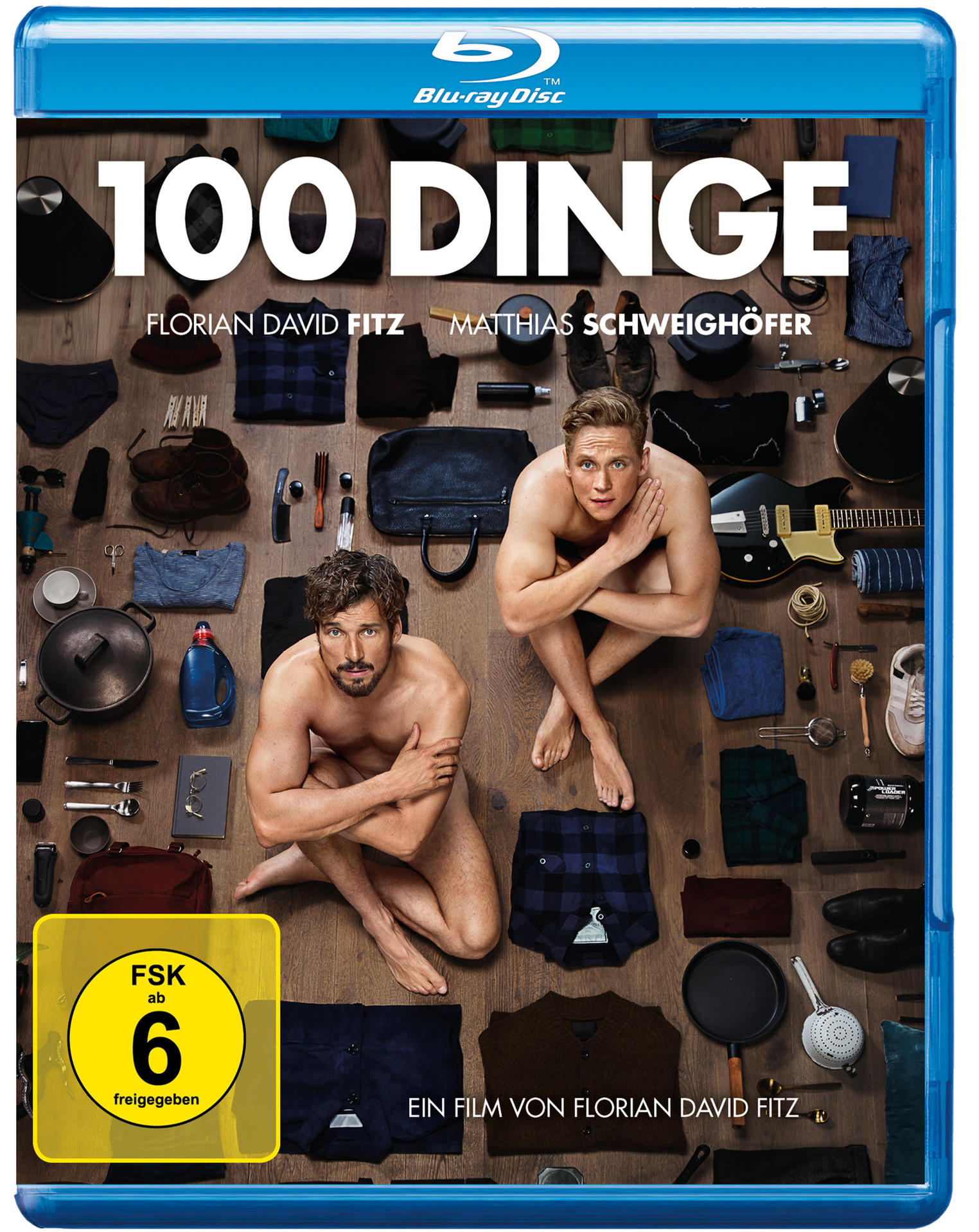 Filmposter von 100 Dinge. Zwei Männer auf Holzboden, Gegenstände verstreut.