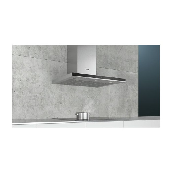 Una campana extractora plateada sobre una estufa y una olla sobre una superficie blanca.