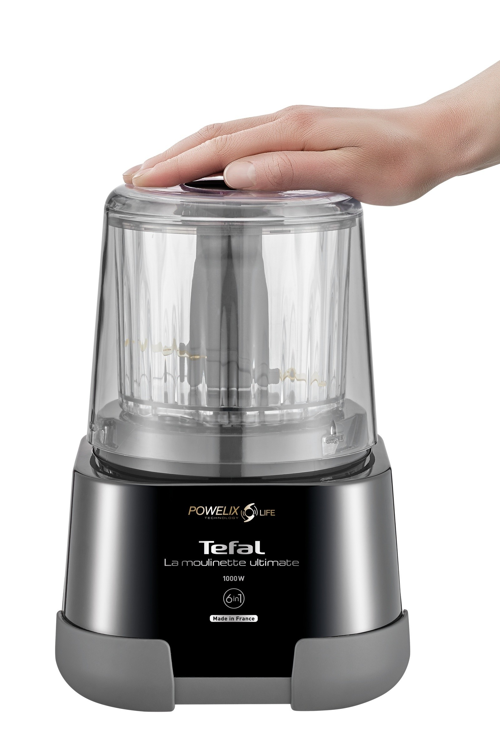 Eine Hand liegt auf einem Tefal-Foodprozessor. Er ist schwarz und grau mit einem transparenten Deckel.