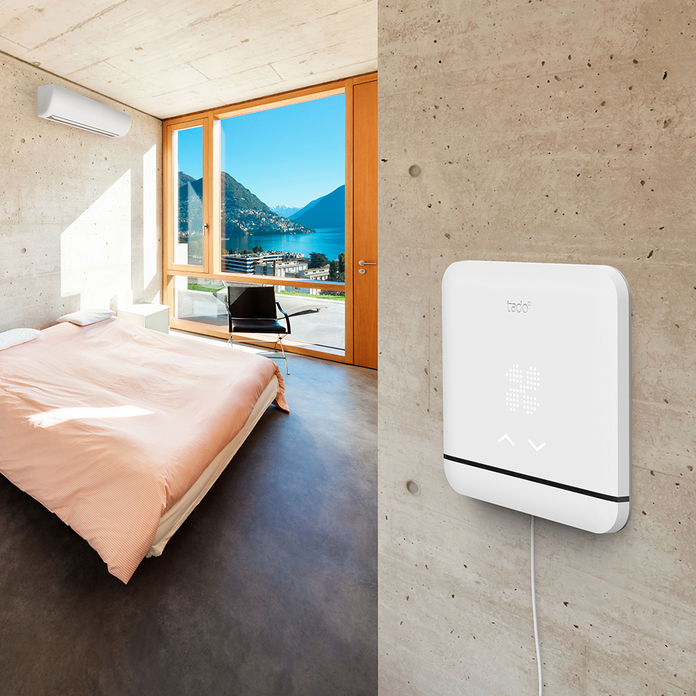 Schlafzimmer mit Bett, Fenster mit Seeblick und einem intelligenten Thermostat an der Wand.