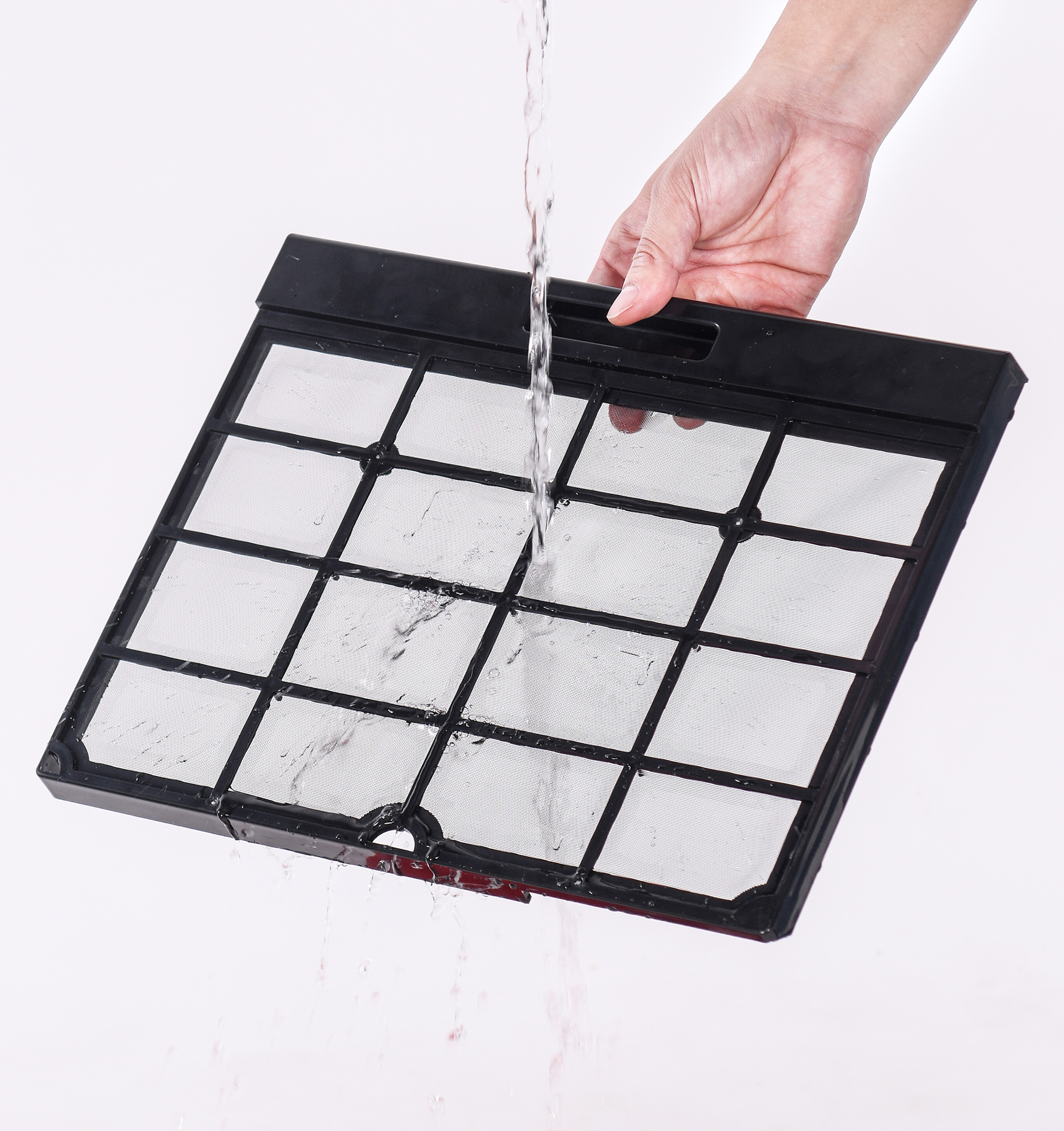 Hand holding a black filter, water is pouring on it. White background. 