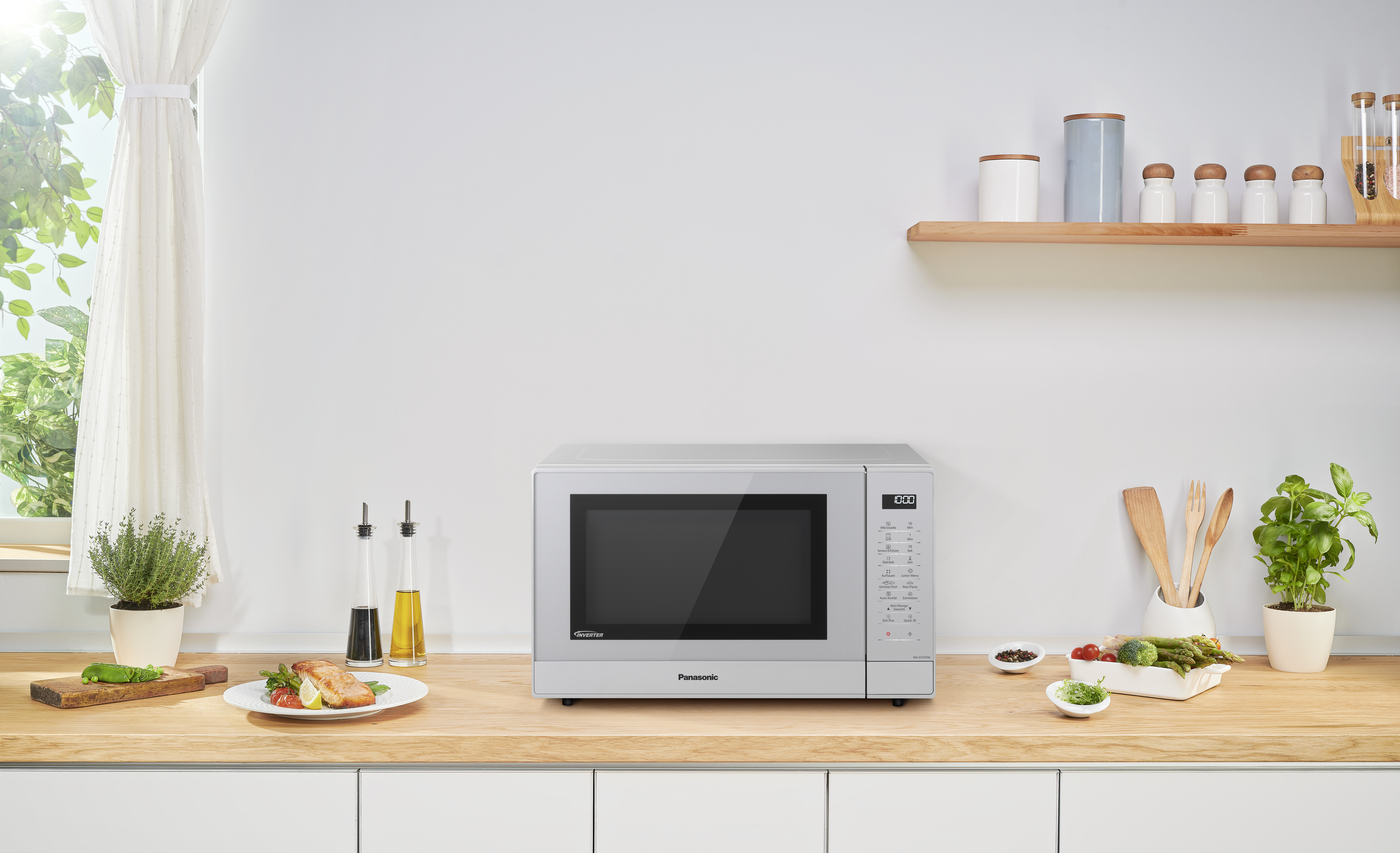 Eine silberne Panasonic Mikrowelle auf einer hölzernen Arbeitsplatte mit verschiedenen Küchenutensilien.