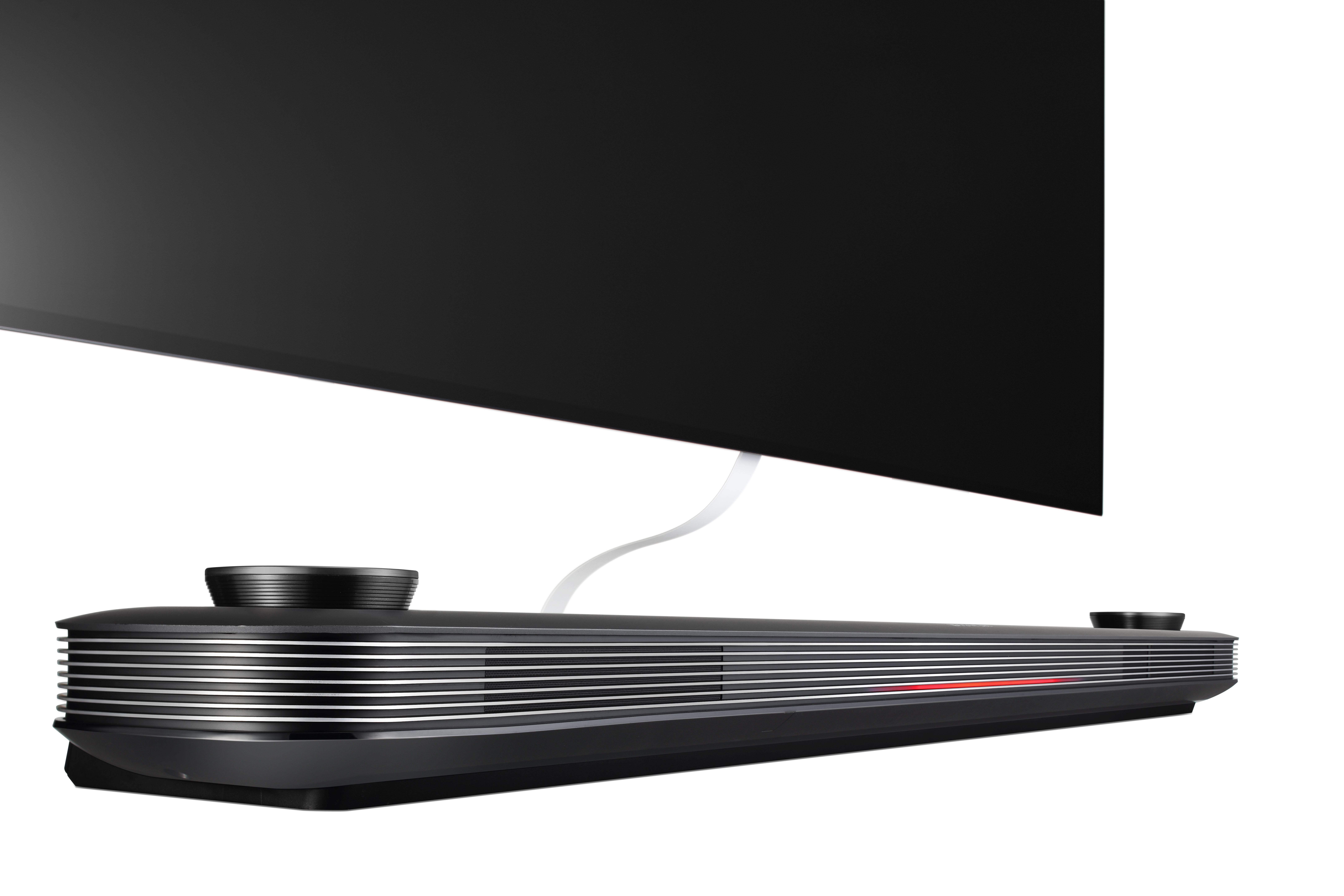 Barra de sonido negra y plateada con un televisor encima, conectado por cable blanco.