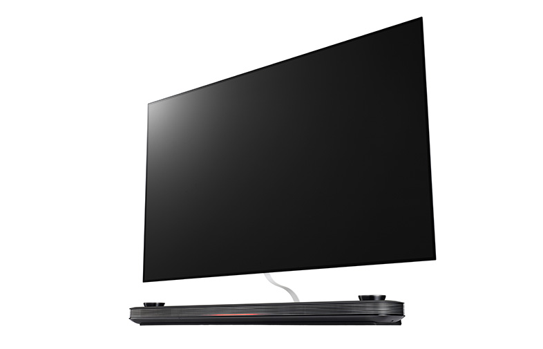 Un televisor grande, negro y delgado sobre una base oscura, inclinado ligeramente hacia el espectador.