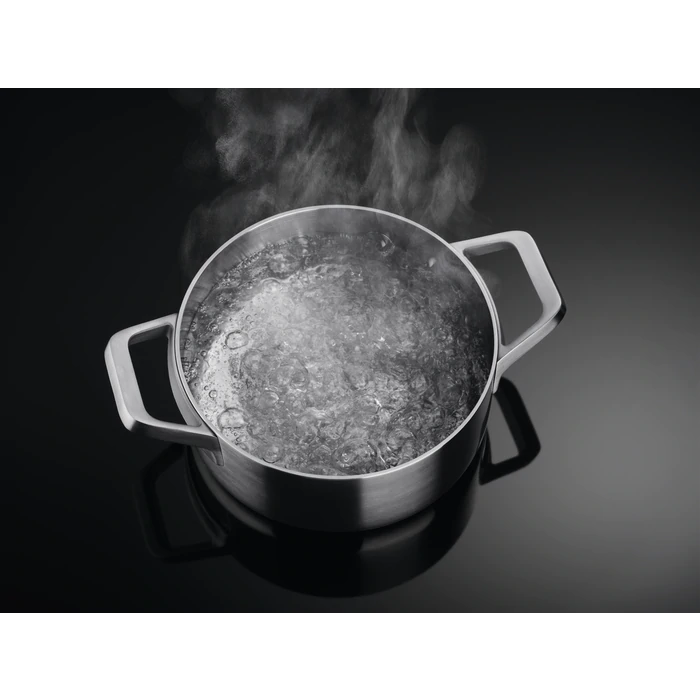 A stainless steel pot with boiling water and steam against a black background.