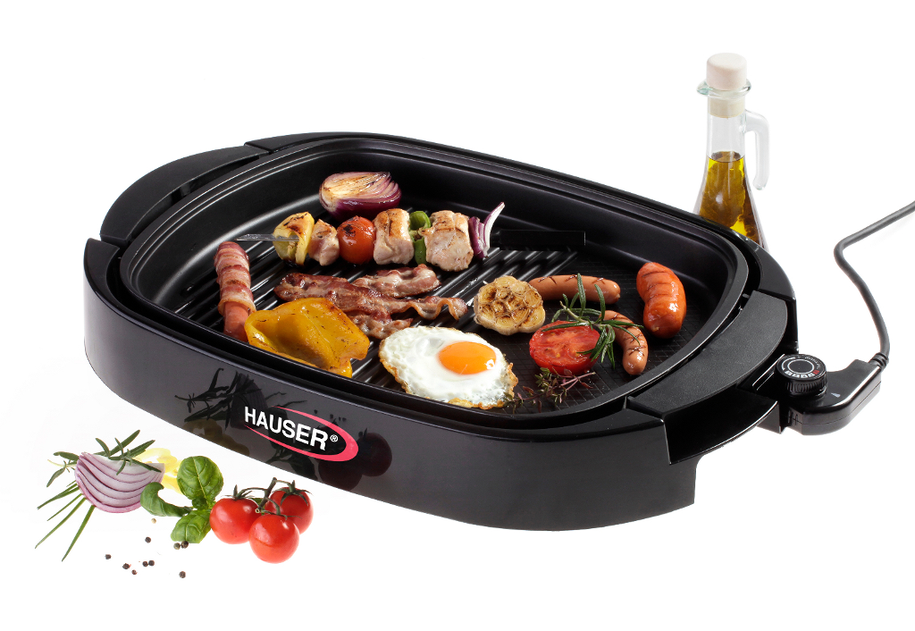 Fekete elektromos grill étellel. Tartalmaz kolbászt, szalonnát, tojást és zöldségeket. Fehér háttér.