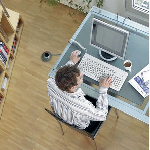 Ein Mann, der an einem Computer an einem Schreibtisch arbeitet, von oben gesehen.