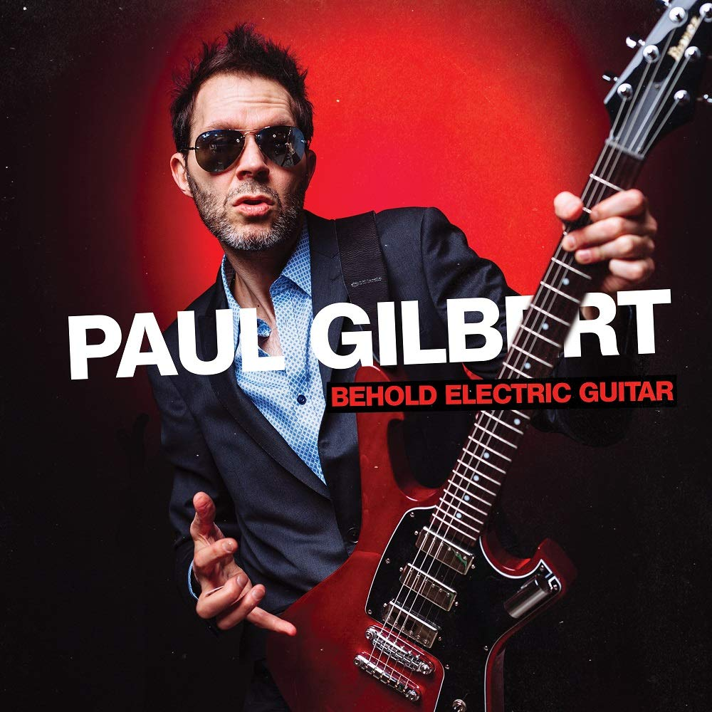 Paul Gilbert egy vörös gitárt tart a 'Behold Electric Guitar' album címével, vörös háttér előtt.
